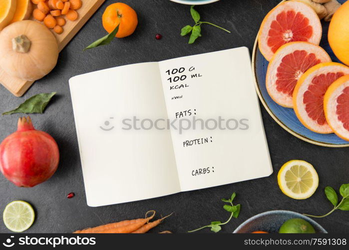 healthy eating, food and diet concept - close up of notebook, fruits and vegetables on slate table top. close up of notebook, fruits and vegetables
