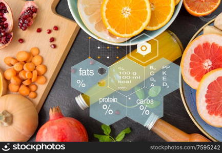 healthy eating, food and diet concept - glass bottles of fruit and vegetable juices on slate table top over nutritional value chart. glass bottles of fruit and vegetable juices