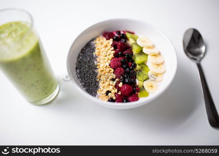 healthy eating, food and diet concept - glass with juice or smoothie and bowl of yogurt with fruits and seeds. smoothie and bowl of yogurt with fruits and seeds