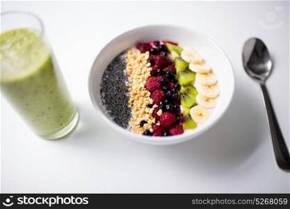 healthy eating, food and diet concept - glass with juice or smoothie and bowl of yogurt with fruits and seeds. smoothie and bowl of yogurt with fruits and seeds