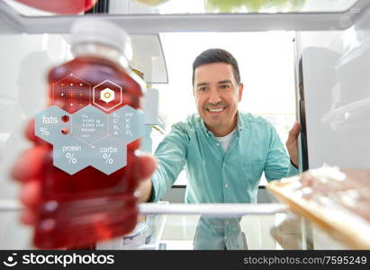 healthy eating, food and diet concept - happy smiling middle-aged man taking bottle of juice from fridge at home kitchen over nutritional value chart. man taking juice from fridge at home kitchen