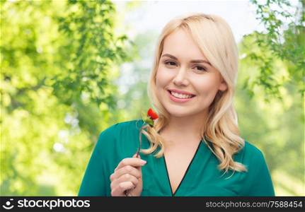 healthy eating, food and diet concept - happy smiling young woman eating vegetables with fork over green natural background. smiling young woman eating vegetables with fork