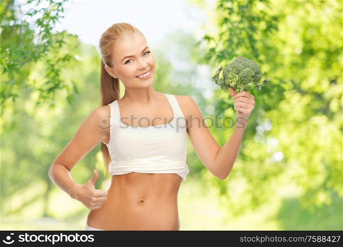 healthy eating, food and diet concept - happy smiling young woman holding broccoli over green natural background. happy smiling young woman with broccoli