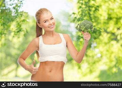 healthy eating, food and diet concept - happy smiling young woman holding broccoli over green natural background. happy smiling young woman with broccoli