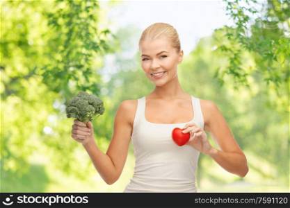 healthy eating, food and diet concept - happy smiling young woman holding red heart and broccoli over green natural background. happy smiling young woman with heart and broccoli