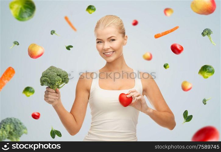 healthy eating, food and diet concept - happy smiling young woman holding red heart and broccoli. happy smiling young woman with heart and broccoli