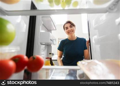 healthy eating, food and diet concept - happy woman at open fridge at home kitchen. happy woman at open fridge at home kitchen