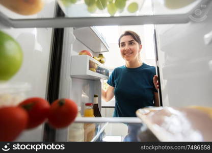healthy eating, food and diet concept - happy woman at open fridge at home kitchen. happy woman at open fridge at home kitchen