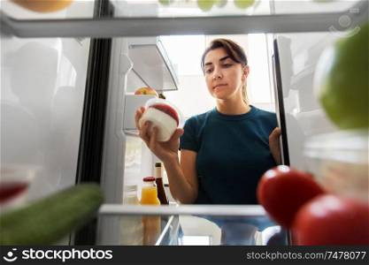 healthy eating, food and diet concept - woman taking yoghurt from fridge at home kitchen. woman taking food from fridge at home