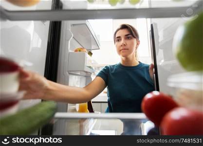 healthy eating, food and diet concept - woman taking yoghurt from fridge at home kitchen. woman taking food from fridge at home