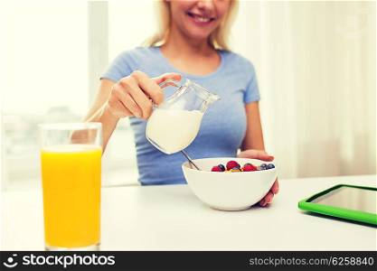 healthy eating, food and people concept - close up of woman pouring milk from jug to bowl with breakfast at home