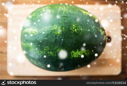 healthy eating, food and vegetarian concept - close up of watermelon on wooden cutting board over snow. close up of watermelon on cutting board