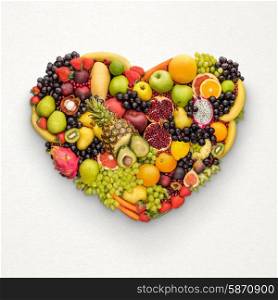 Healthy eating food concept; heart symbol made of fresh fruits that reduce death risk, on light grey background.