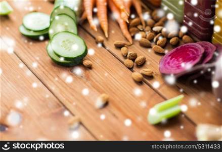 healthy eating, food, cooking and vegetarian concept - different vegetables and almond nuts on wooden table over snow. different vegetables and almond nuts on wood