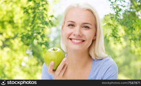 healthy eating, food, diet and people concept - happy smiling woman with green apple over natural background. happy woman with green apple
