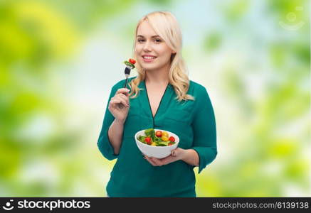 healthy eating, food, diet and people concept - smiling young woman eating vegetable salad with fork over green natural background