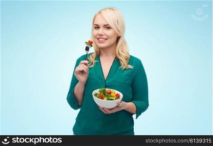 healthy eating, food, diet and people concept - smiling young woman eating vegetable salad with fork over blue background