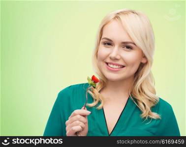 healthy eating, food, diet and people concept - smiling young woman eating vegetable salad with fork over green natural background
