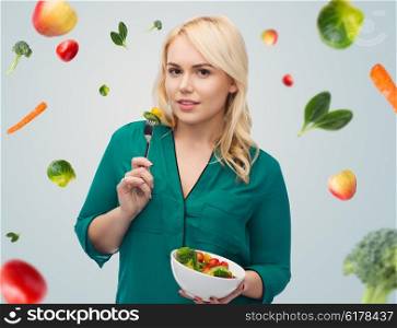 healthy eating, food, diet and people concept - smiling young woman eating vegetable salad with fork