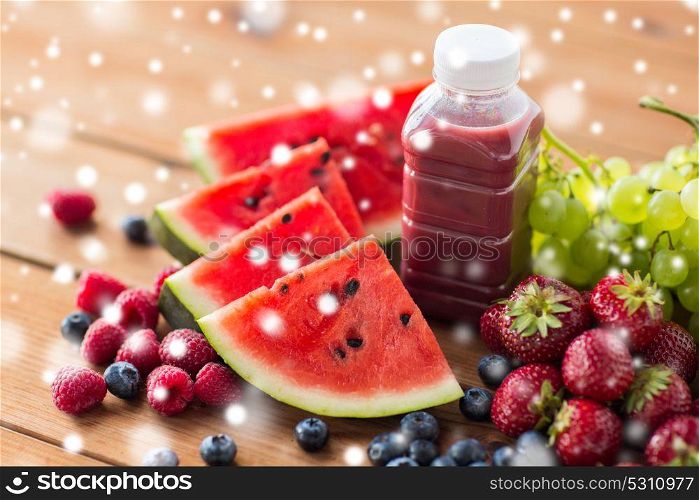 healthy eating, food, diet and vegetarian concept - bottle with fruit and berry juice or smoothie on wooden table over snow. bottle with fruit and berry juice or smoothie