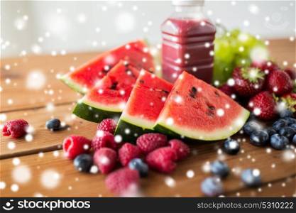healthy eating, food, diet and vegetarian concept - watermelon slices, bottle of fruit juice or smoothie and berries on wooden table over snow. watermelon, bottle of fruit juice and berries