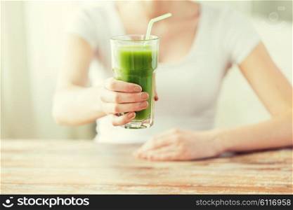 healthy eating, food, diet, detox and people concept - close up of woman hands with green juice on wooden table