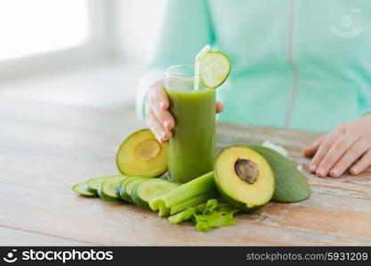 healthy eating, food, dieting and people concept - close up of woman hands with green fresh juice and vegetables sitting at table