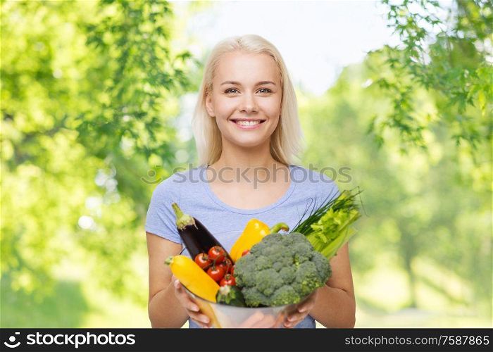 healthy eating, food, dieting and people concept - happy smiling young woman with bowl of vegetables over green natural background. smiling young woman with vegetables