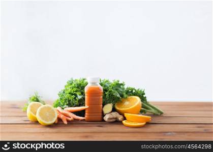 healthy eating, food, dieting and vegetarian concept - bottle with carrot juice, fruits and vegetables on wooden table