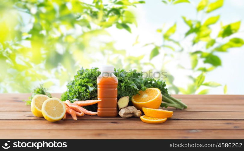 healthy eating, food, dieting and vegetarian concept - bottle with carrot juice, fruits and vegetables on wooden table over green natural background