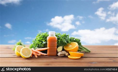 healthy eating, food, dieting and vegetarian concept - bottle with carrot juice, fruits and vegetables on wooden table over blue sky background