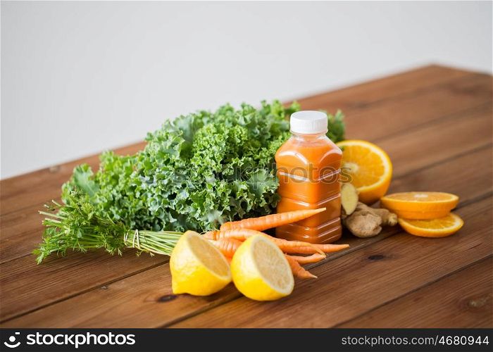 healthy eating, food, dieting and vegetarian concept - bottle with carrot juice, fruits and vegetables on wooden table