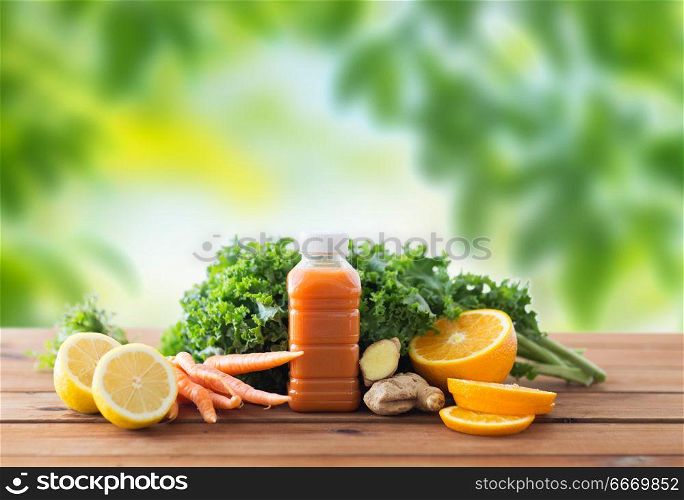 healthy eating, food, dieting and vegetarian concept - bottle with carrot juice, fruits and vegetables on wooden table over green natural background. bottle with carrot juice, fruits and vegetables. bottle with carrot juice, fruits and vegetables