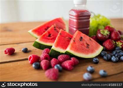 healthy eating, food, dieting and vegetarian concept - bottle with fruit and berry juice or smoothie on wooden table