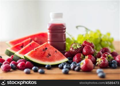 healthy eating, food, dieting and vegetarian concept - bottle with fruit and berry juice or smoothie on wooden table. bottle with fruit and berry juice or smoothie