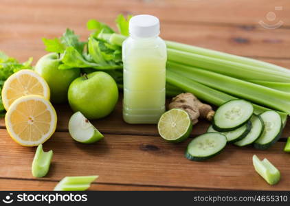 healthy eating, food, dieting and vegetarian concept - bottle with green juice, fruits and vegetables on wooden table