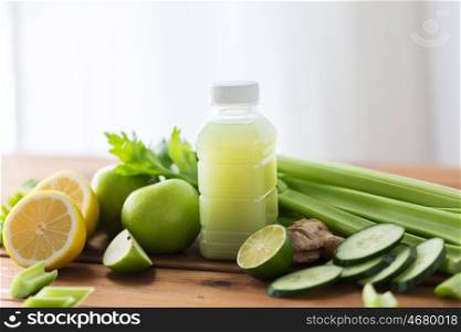 healthy eating, food, dieting and vegetarian concept - bottle with green juice, fruits and vegetables on wooden table