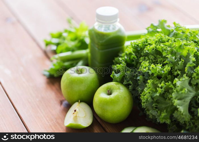 healthy eating, food, dieting and vegetarian concept - bottle with green juice, fruits and vegetables on wooden table