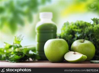 healthy eating, food, dieting and vegetarian concept - bottle with green juice, fruits and vegetables on wooden table over green natural background. close up of bottle with green juice and vegetables. close up of bottle with green juice and vegetables