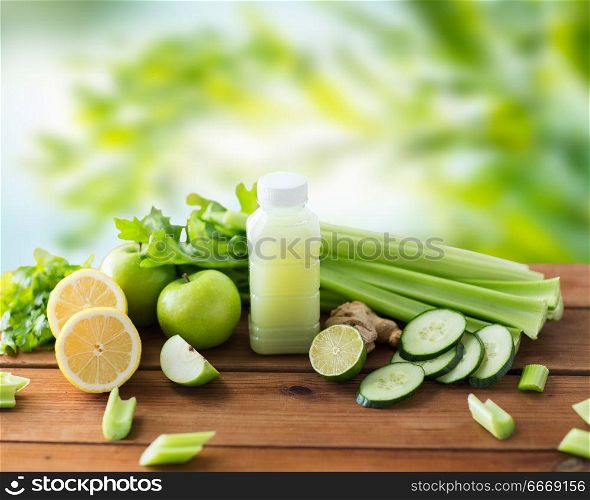 healthy eating, food, dieting and vegetarian concept - bottle with juice, fruits and vegetables on wooden table over green natural background. close up of bottle with green juice and vegetables. close up of bottle with green juice and vegetables