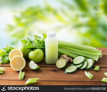 healthy eating, food, dieting and vegetarian concept - bottle with juice, fruits and vegetables on wooden table over green natural background. close up of bottle with green juice and vegetables. close up of bottle with green juice and vegetables