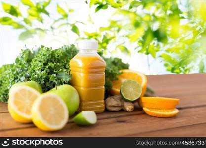 healthy eating, food, dieting and vegetarian concept - bottle with orange juice, fruits and vegetables on wooden table over green natural background