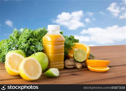 healthy eating, food, dieting and vegetarian concept - bottle with orange juice, fruits and vegetables on wooden table over blue sky background