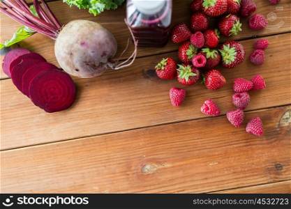 healthy eating, food, dieting and vegetarian concept - close up of bottle with beetroot juice, fruits and vegetables on wooden table