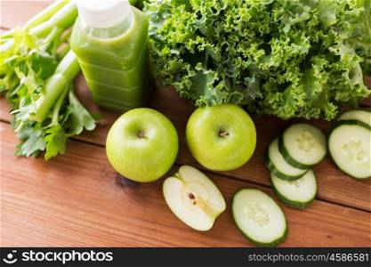 healthy eating, food, dieting and vegetarian concept - close up of bottle with green juice, fruits and vegetables on wooden table