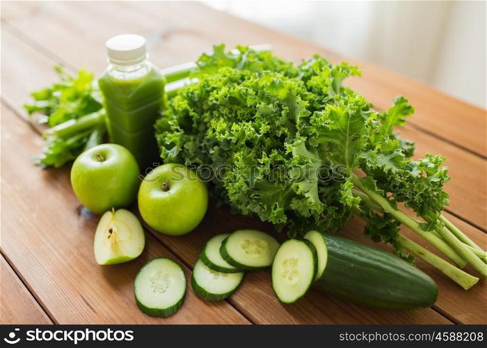 healthy eating, food, dieting and vegetarian concept - close up of bottle with green juice, fruits and vegetables on wooden table