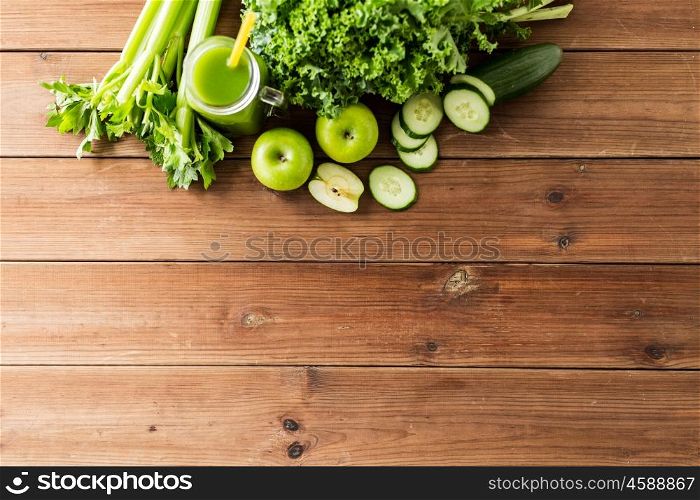 healthy eating, food, dieting and vegetarian concept - close up of bottle with green juice, fruits and vegetables on wooden table. close up of jug with green juice and vegetables
