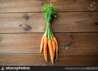 healthy eating, food, dieting and vegetarian concept - close up of carrot bunch on wooden table