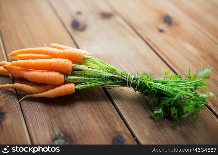 healthy eating, food, dieting and vegetarian concept - close up of carrot bunch on wooden table