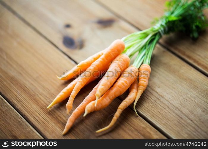 healthy eating, food, dieting and vegetarian concept - close up of carrot bunch on wooden table